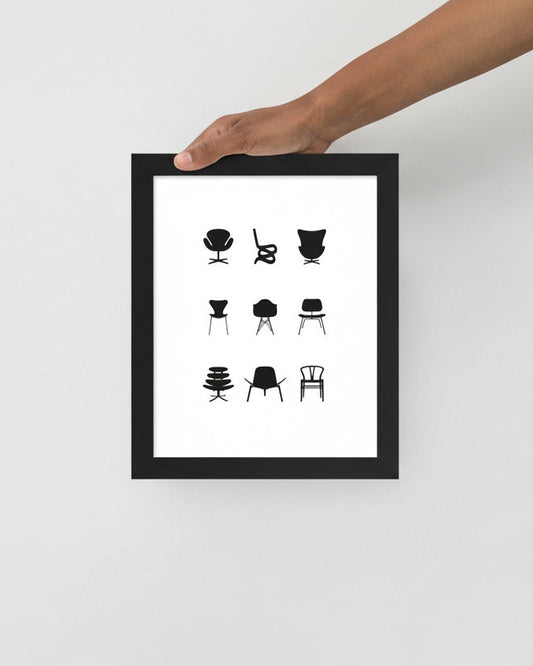 Framed artwork with black and white chair illustrations held by a hand on a light gray background