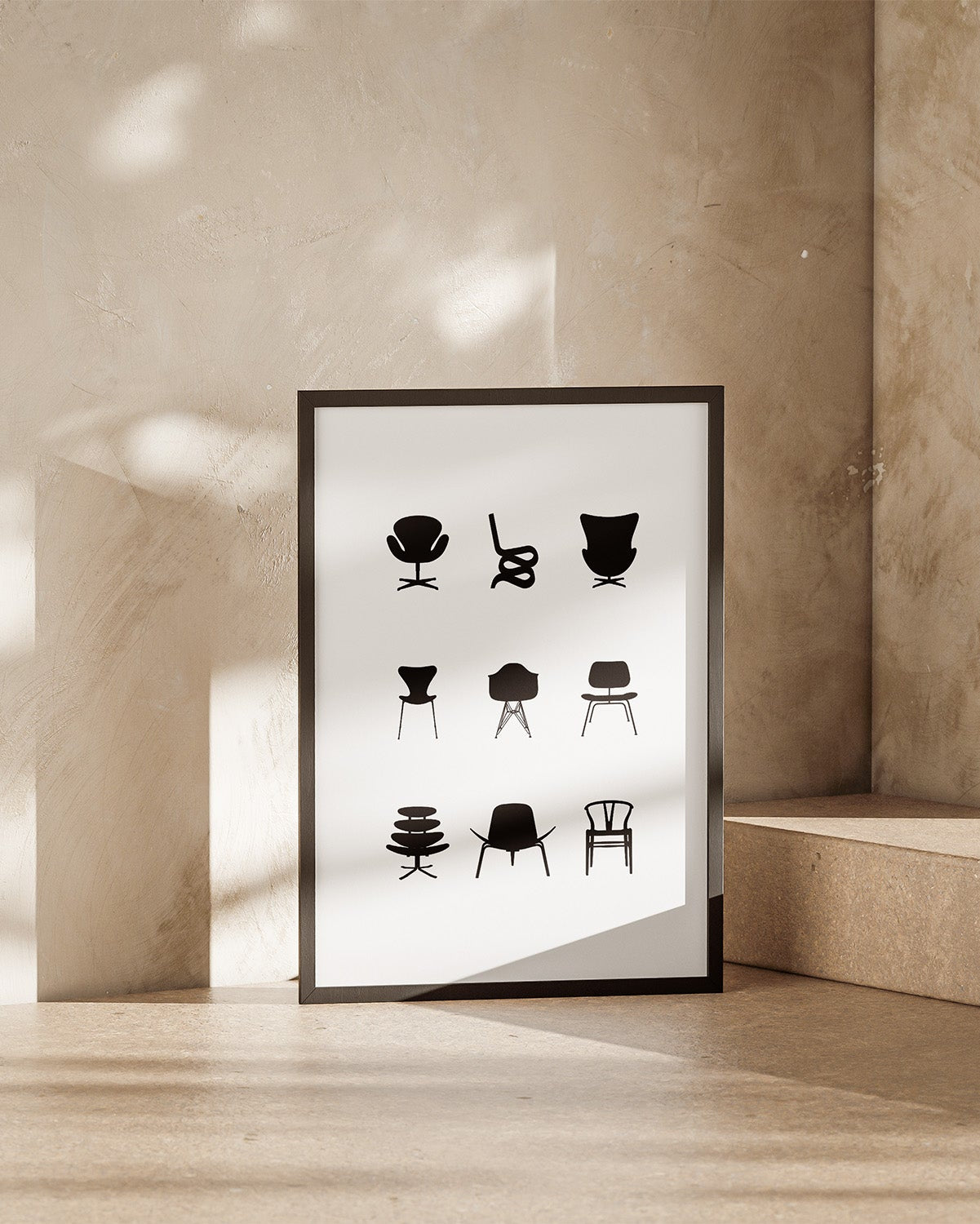 Framed poster with black and white illustrations of iconic eames chairs on a beige wall.