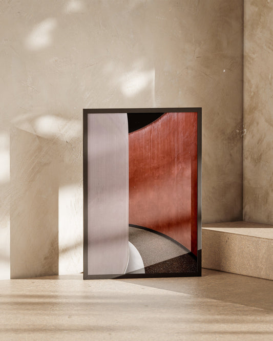 Framed artwork leaning against a beige wall with sunlight casting shadows.