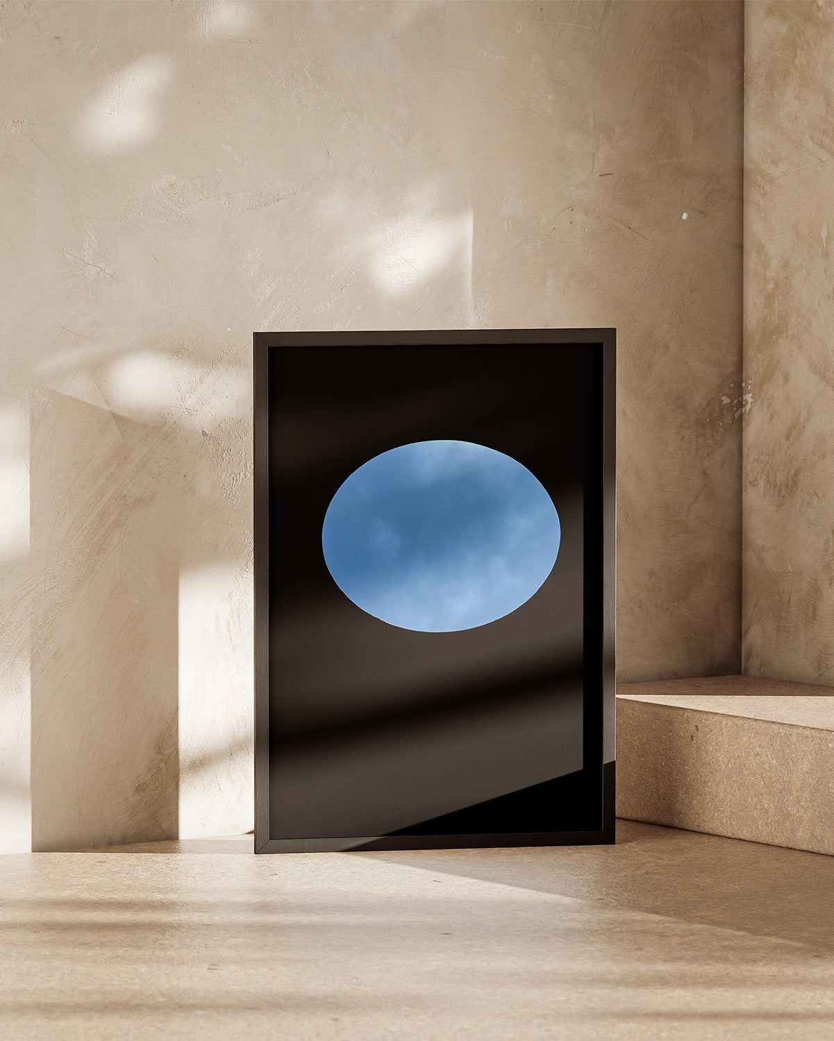 Framed artwork of oculous at skyspace three gems with a blue circular design on a beige wall.