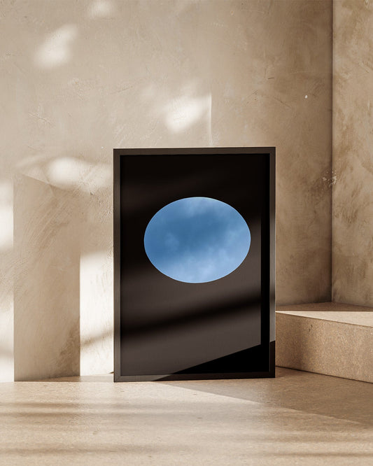 Framed artwork of oculous at skyspace three gems with a blue circular design on a beige wall.